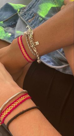 two people wearing bracelets sitting next to each other