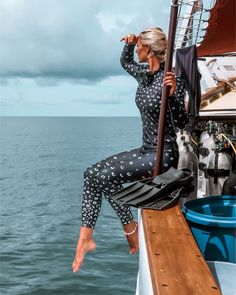 a woman sitting on top of a boat next to the ocean