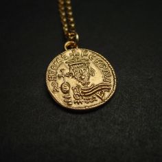 "Hand carved dainty pendant from a medieval coin. Byzantine coin reproduction of Phocas (602-610 A.D.), emperor of the Byzantine Roman empire. Originally minted in Constantinople (Istanbul). Latin inscription: \"ON FOCAS PЄRP AVI\" - Hand carved charm. - Solid yellow bronze also called jeweler gold bronze charm. - Coin is 1/2\" - Signed in the back by artist. - Soldered eyelet on top. - 14k gold filled chain. - Gold filled has 100 times more gold than plated. Does not rub off. - Lobster claw cla Byzantine Style Medallion Coin Necklace, Byzantine Coin Necklace As A Gift, Byzantine Style Coin Necklace As A Gift, Byzantine Style Coin Necklace For Gift, Medieval Style Gold Engraved Necklace, Engraved Byzantine Medallion Necklaces, Ancient Coin, Greek Coins, Roman Coins