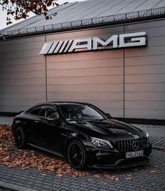 a black car parked in front of a building with the word amg on it