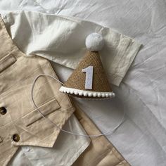 a white shirt with a tan jacket and a brown hat on top of it next to a pair of headphones