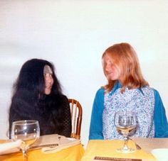 two women sitting at a table with wine glasses