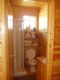 there is a toilet and sink in this small bathroom with wood paneling on the walls