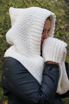 a woman wearing a white knitted hood and mittens with her hands on her face