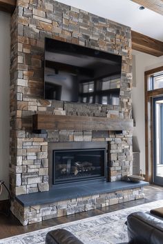 a living room with a large stone fireplace and flat screen tv mounted on the wall