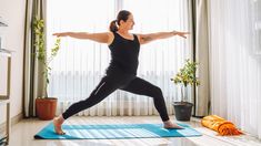 a woman is doing yoga in the living room with her arms spread out and legs crossed