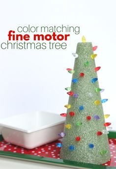 a green christmas tree sitting on top of a table next to a white plate and bowl