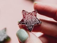 a hand holding a small red and white glittered star brooch on it's finger