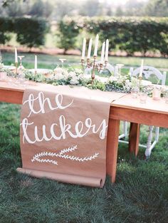 a wooden table topped with flowers and candles next to a sign that says the tuckers