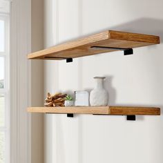 two wooden shelves with vases and candles on them in front of a white wall