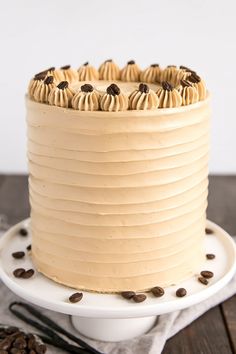 a cake with frosting and chocolate chips on top sits on a plate next to some coffee beans