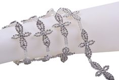 three bracelets with crosses on them are sitting on a white armband, and one has a chain attached to it