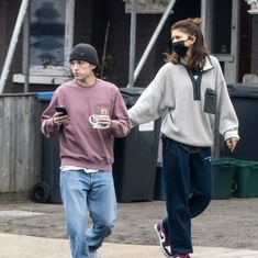 a man and woman walking down the street while using their cell phones to check their messages