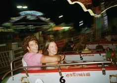 a man and woman are riding on a roller coaster at an amusement park in the night