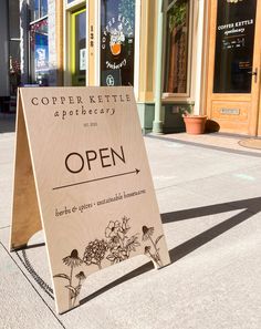 an open sign sitting on the sidewalk in front of a store