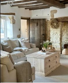 a living room filled with furniture and a fire place in front of a stone wall