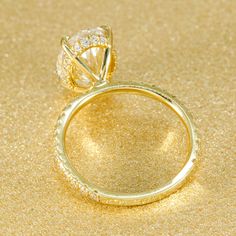 a yellow gold ring with a diamond on the top and side, sitting on a golden surface