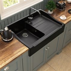 a black kitchen sink sitting on top of a counter next to a wooden countertop