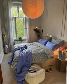 a bed room with a neatly made bed next to a window and a lamp hanging above it