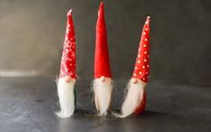 three small red and white gnomes sitting next to each other on top of a table