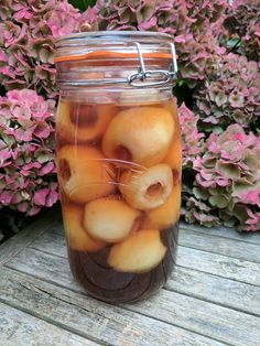 a jar filled with apples sitting on top of a wooden table