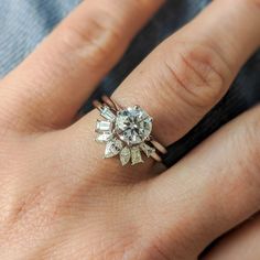 a woman's hand with a diamond ring on top of her finger and an engagement band