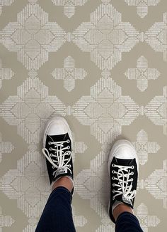 a person wearing black and white sneakers standing on a patterned floor