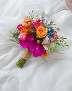 a bridal bouquet on a bed with white sheets and flowers in the foreground