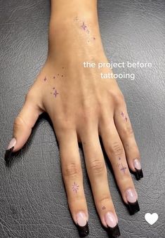 a woman's hand with pink nail polish and stars on her left wrist, next to the words the project before tattooing