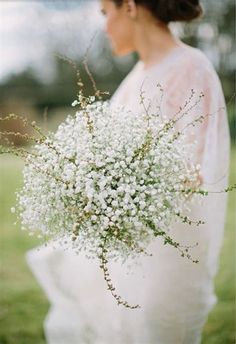 a woman in a white dress holding a bouquet of baby's breathflowers