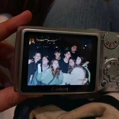 a person is holding up a camera to take a picture with friends in the background