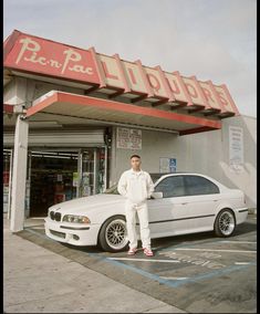 a man standing next to a white car in front of a store