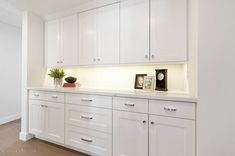 a kitchen with white cabinetry and counter tops is shown in this image, there are two clocks on the wall