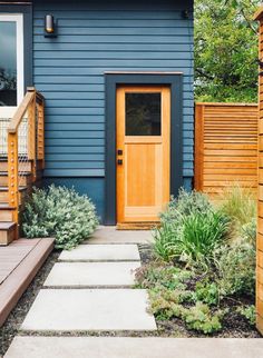 a blue house with wooden steps leading to the front door and side porch area next to it