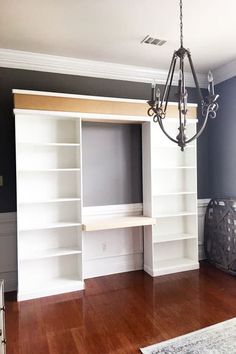 a chandelier hanging from the ceiling in a room with white bookshelves