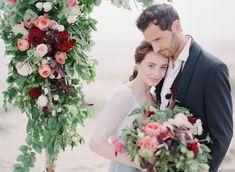 a bride and groom standing under a floral arch