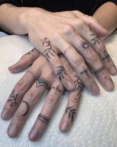 two hands with tattoos on them sitting on top of a white bed next to each other