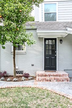 a house with a black front door and brick steps leading up to the front door