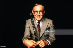 an older man in a suit and tie holding a saxophone