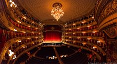 an auditorium with chandeliers and red curtains is seen from the top floor looking down