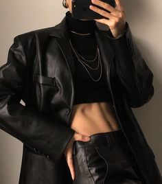 a woman taking a selfie while wearing black leather pants and a turtle neck top