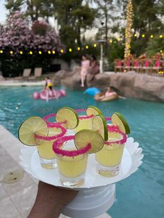 a person holding a tray with drinks near a swimming pool