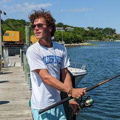 a man standing on a dock holding a fishing pole