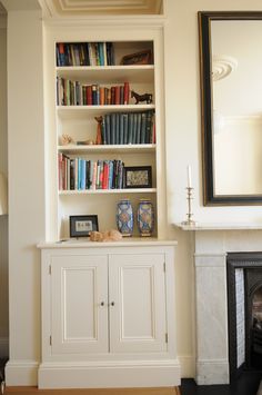 a living room with a fireplace and bookshelf next to a mirror on the wall