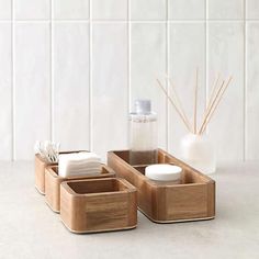 three wooden containers with soap, toothbrushes and other items in them on a counter