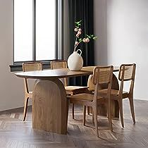 a vase with flowers sitting on top of a wooden table next to two chairs and a window