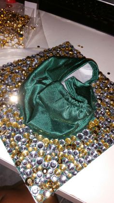 a green purse sitting on top of a table covered in gold and silver sequins