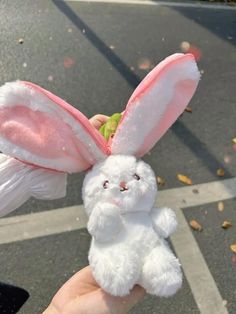 someone is holding up a stuffed animal bunny in the street with leaves on it's ears