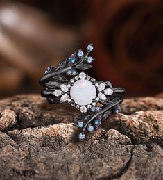 an opal and diamond ring sitting on top of a rock