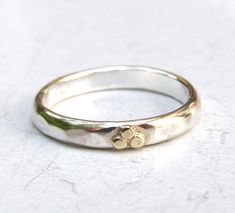 a close up of a silver ring on a white surface with a gold flower in the middle